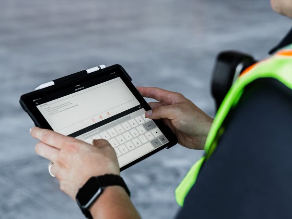 Construction worker using Raken's field report app on tablet.